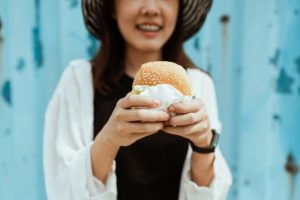 crop unrecognizable woman with delicious hamburger near blue ribbed wall