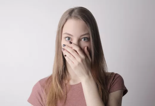 young amazed woman in casual wear covering mouth while keeping secret