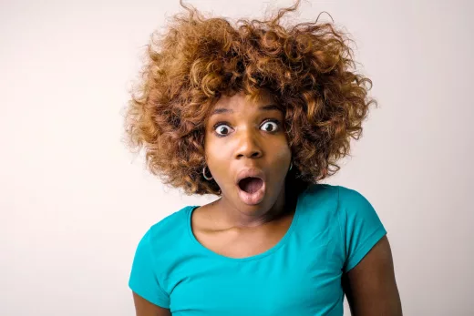 portrait photo of shocked woman in blue t shirt standing in front of white background